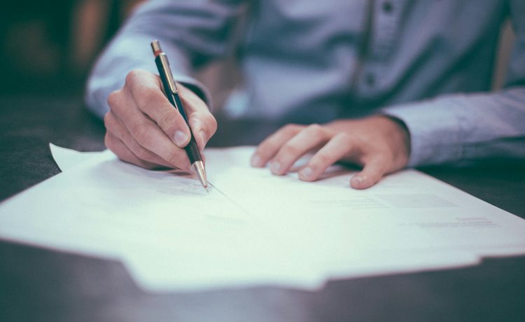 A person signing papers at a desk