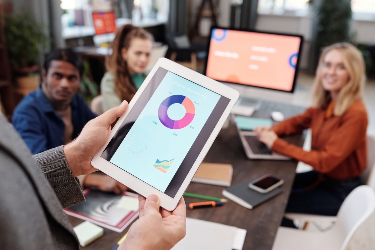 A person holding a tablet with digital marketing pie chart on screen