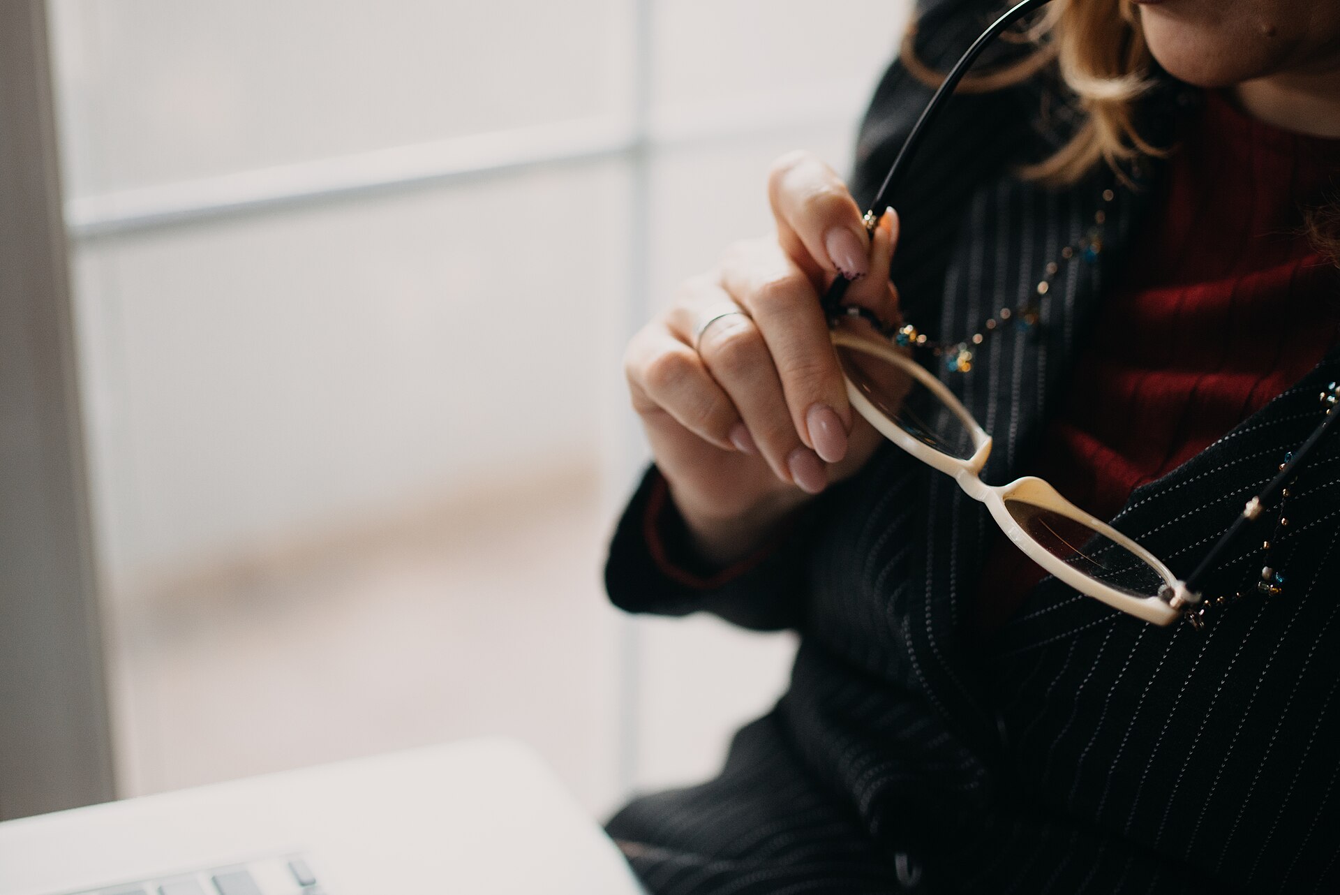 Business professional contemplating while adjusting glasses in a modern office setting during the afternoon