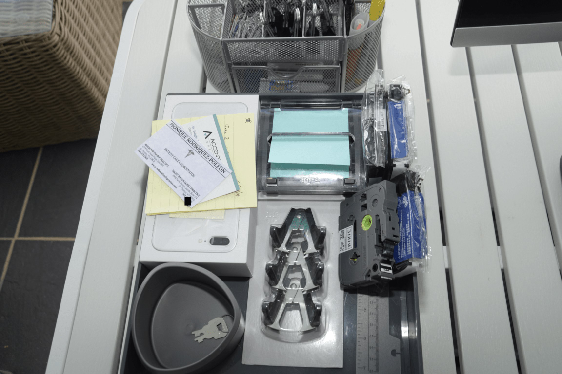 EFTA00003029-Beach-House - Cluttered desk with office supplies including labels tape a phone and a business card