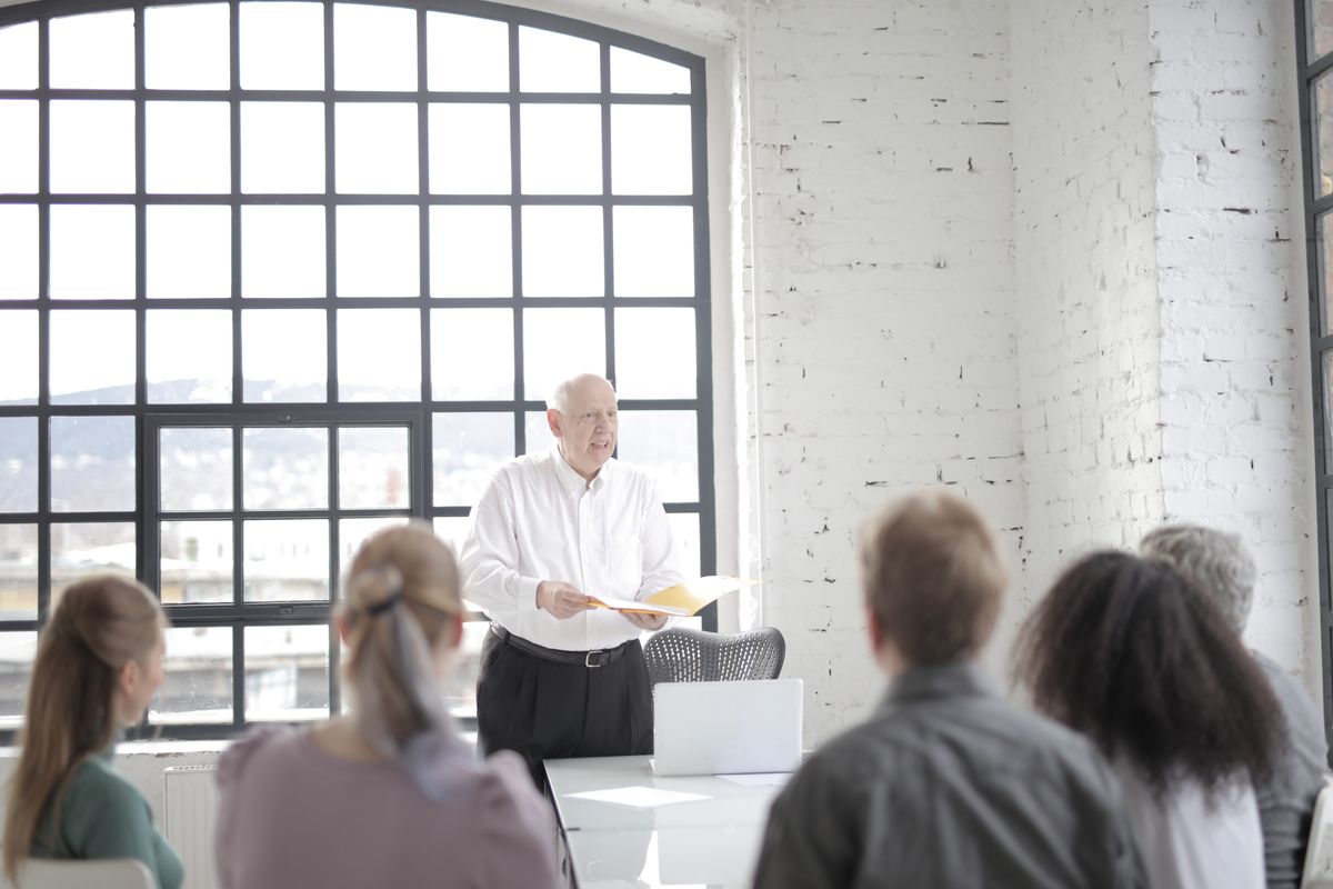 Diverse colleagues listening to senior male executive at meeting in office boardroom