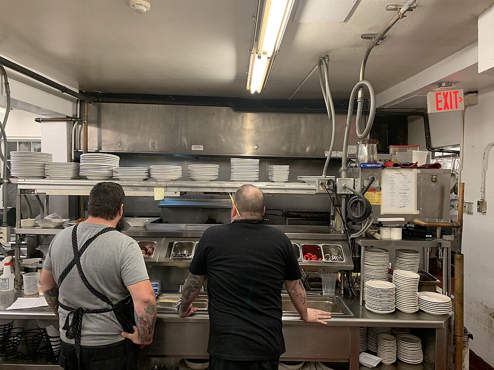 Two cooks at a restaurant kitchen pass