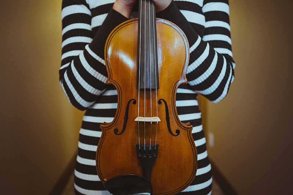 A violin held against a striped jumper